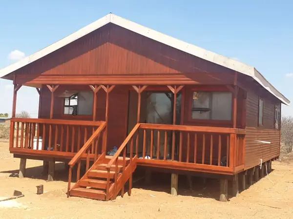 Red log home with front deck and stairs