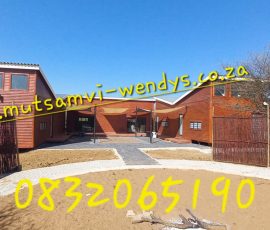 Large custom-built log home with spacious veranda by Mutsamvi Construction.