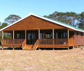 Luxury wooden log home with front deck and covered veranda by Mutsamvi Construction.