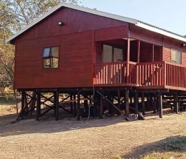 Elevated wooden log home with spacious deck and balcony by Mutsamvi Construction.