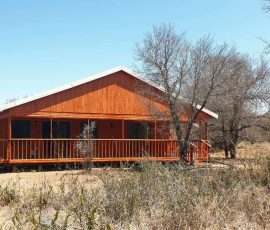 Large timber log home with covered patio and raised foundation.